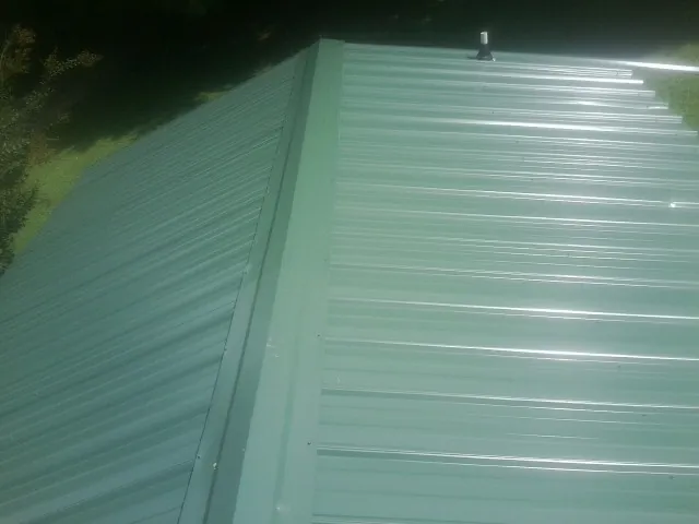New green metal panels meeting at the ridge of a roof — Flat Roof Repair work by our crew in Kennewick