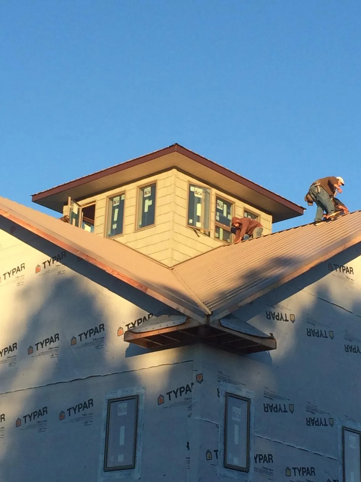 Roofers working around a rooftop cupola on a new metal roof at sunset — Roof Waterproofing in Kennewick by Roofing Brothers
